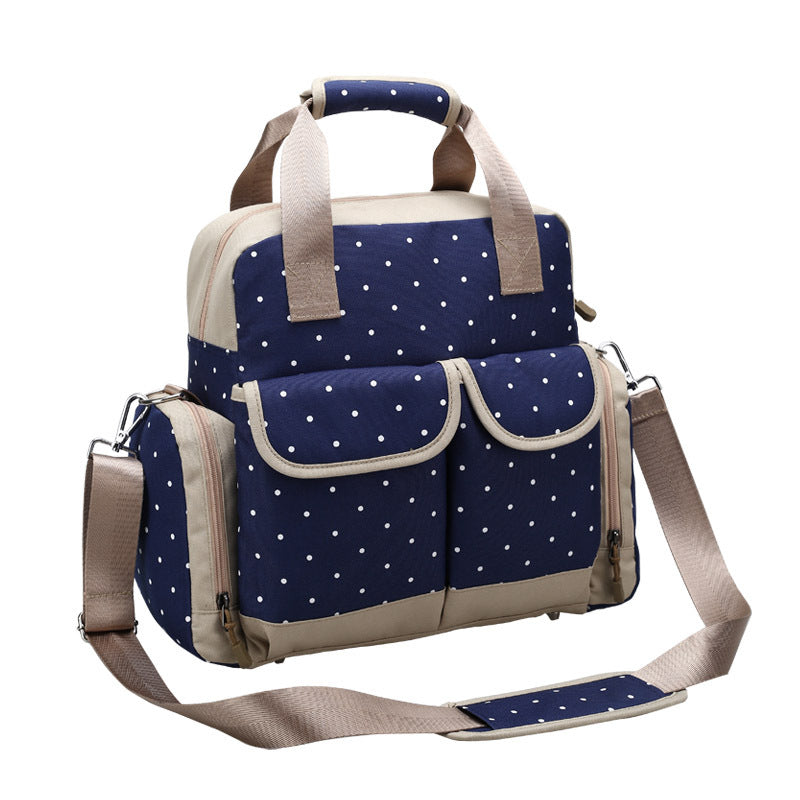 Navy blue polka dot diaper backpack with beige trim, multiple pockets, and shoulder strap.