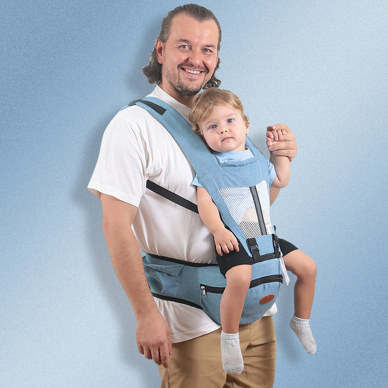 Smiling dad carrying baby in a light blue ergonomic hip seat carrier with mesh panel and storage.