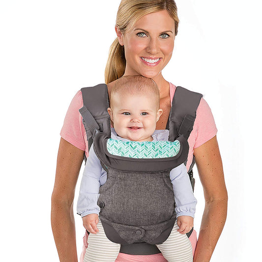 Smiling mom carrying baby in a gray ergonomic carrier with mint green patterned lining.