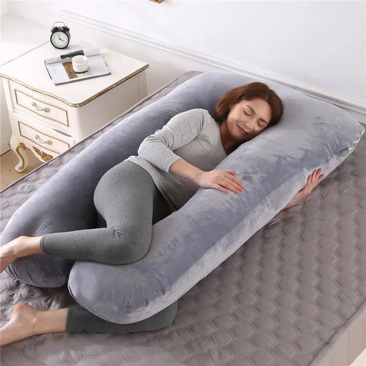 Woman sleeping soundly on a full-body gray suede U-shaped orthopedic pregnancy pillow.