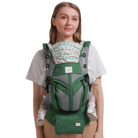 Woman wearing a green ergonomic cotton baby carrier with a floral pattern, suitable for front and back carry.