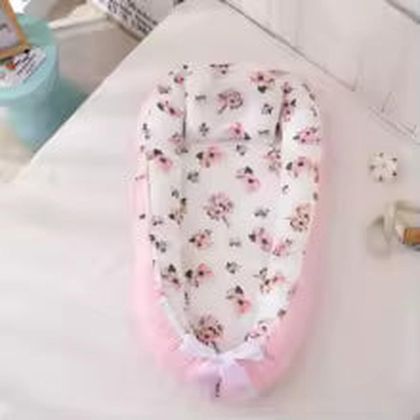 Pink and white baby nest with floral print, adjustable and breathable cotton fabric.