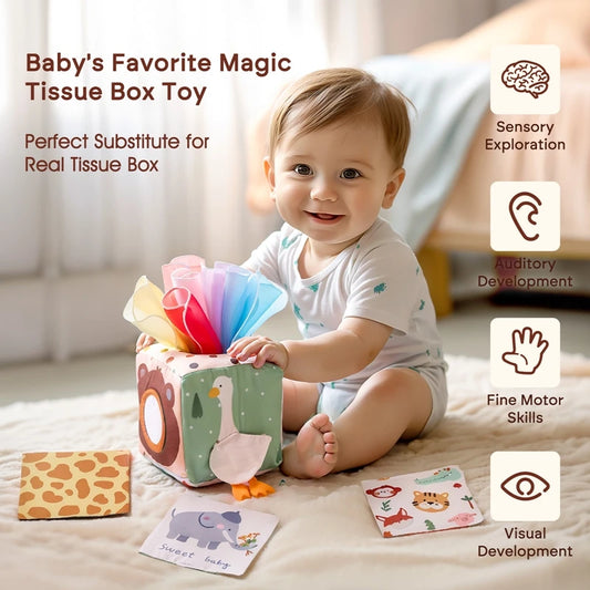 Smiling baby playing with a soft, colorful animal-themed sensory tissue box toy and learning cards.