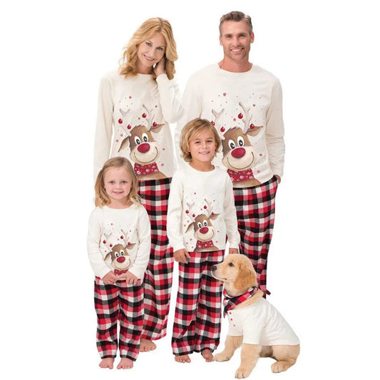 Family wearing matching white and red plaid Christmas pajamas with reindeer design, including a dog.