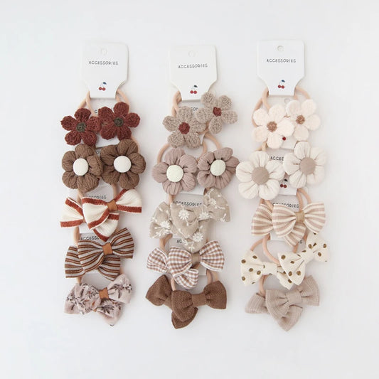 Three sets of 5 handmade floral and bow hair ties for girls in brown, beige, and cream.