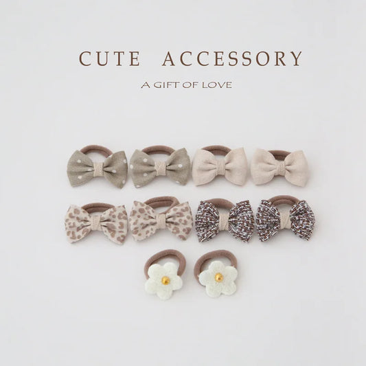10-pack of girls' hair ties and clips: beige bows (polka dot, leopard, tweed) and white flower ties.