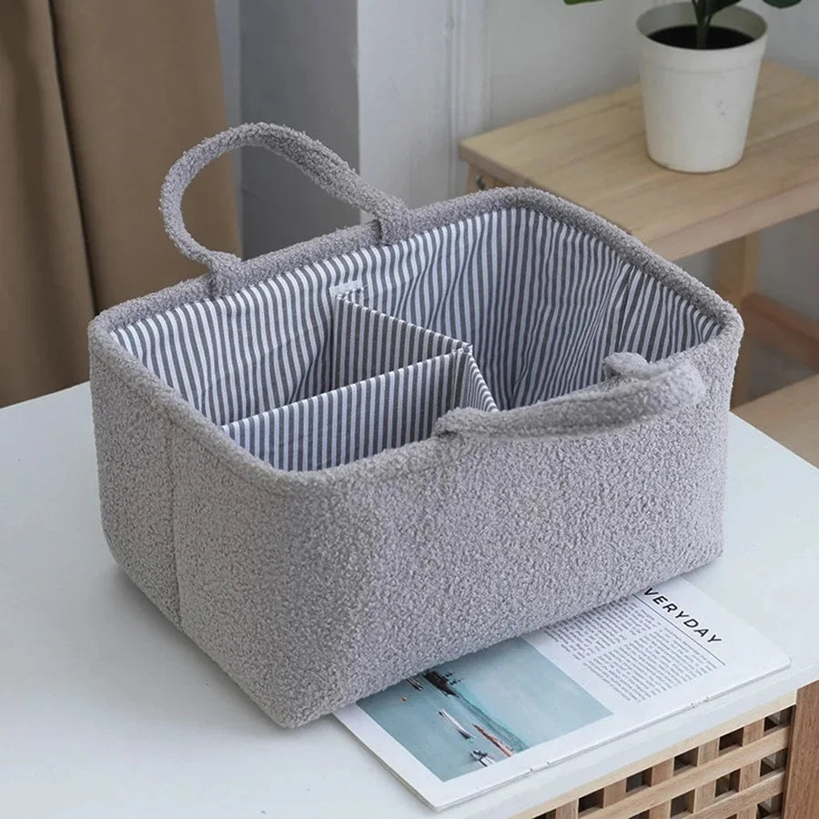 Gray plush baby diaper caddy organizer with striped interior, handles, and multiple compartments.
