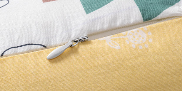 Close-up of a yellow and white patterned nursing pillow with a silver zipper.