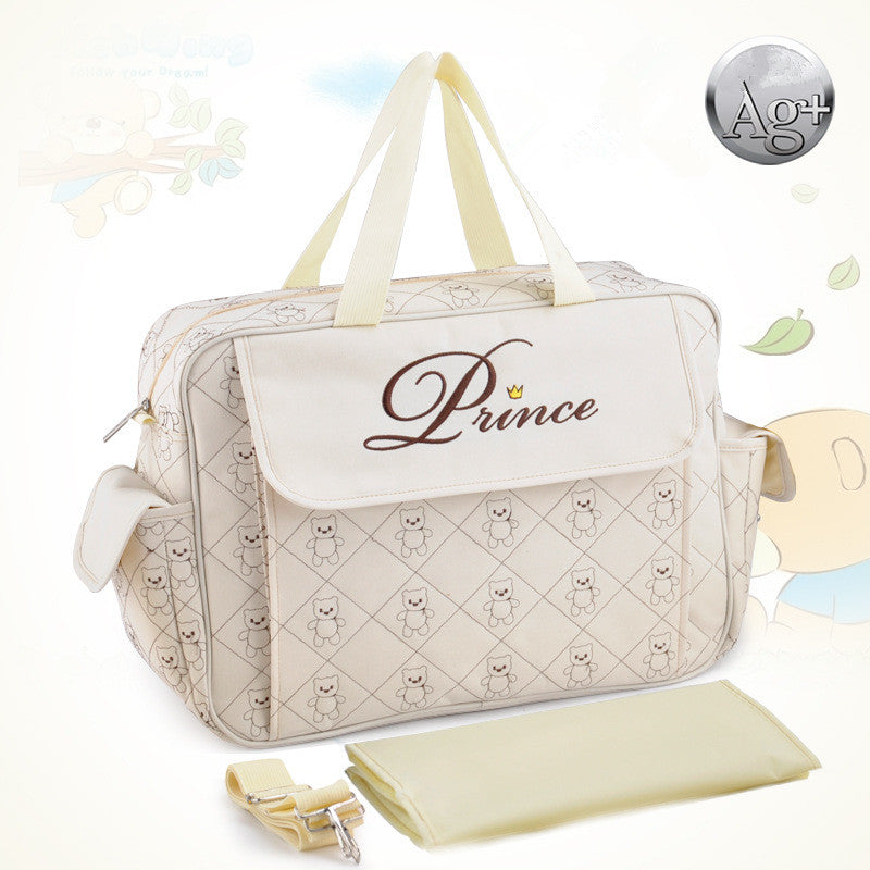 Cream quilted diaper bag with "Prince" embroidery, side pockets, and a matching changing pad.