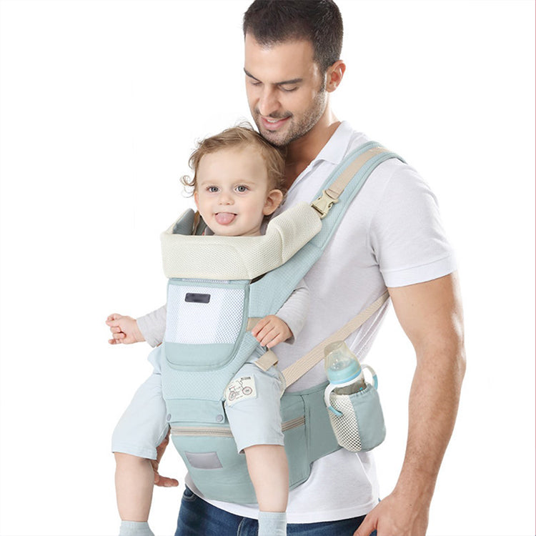 Man carrying a baby in a light blue ergonomic baby carrier with a hip seat and mesh pockets.