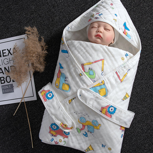 White cotton gauze baby swaddle with colorful construction vehicle print, featuring a hood and adjustable straps.