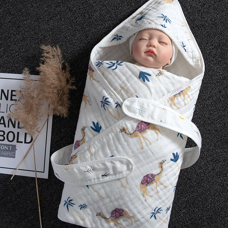 White cotton gauze baby swaddle with camel and palm tree print, featuring a hood and velcro closure.