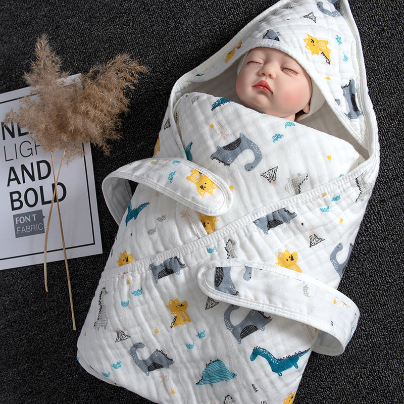 White cotton gauze baby swaddle with hood, featuring colorful dinosaur patterns.