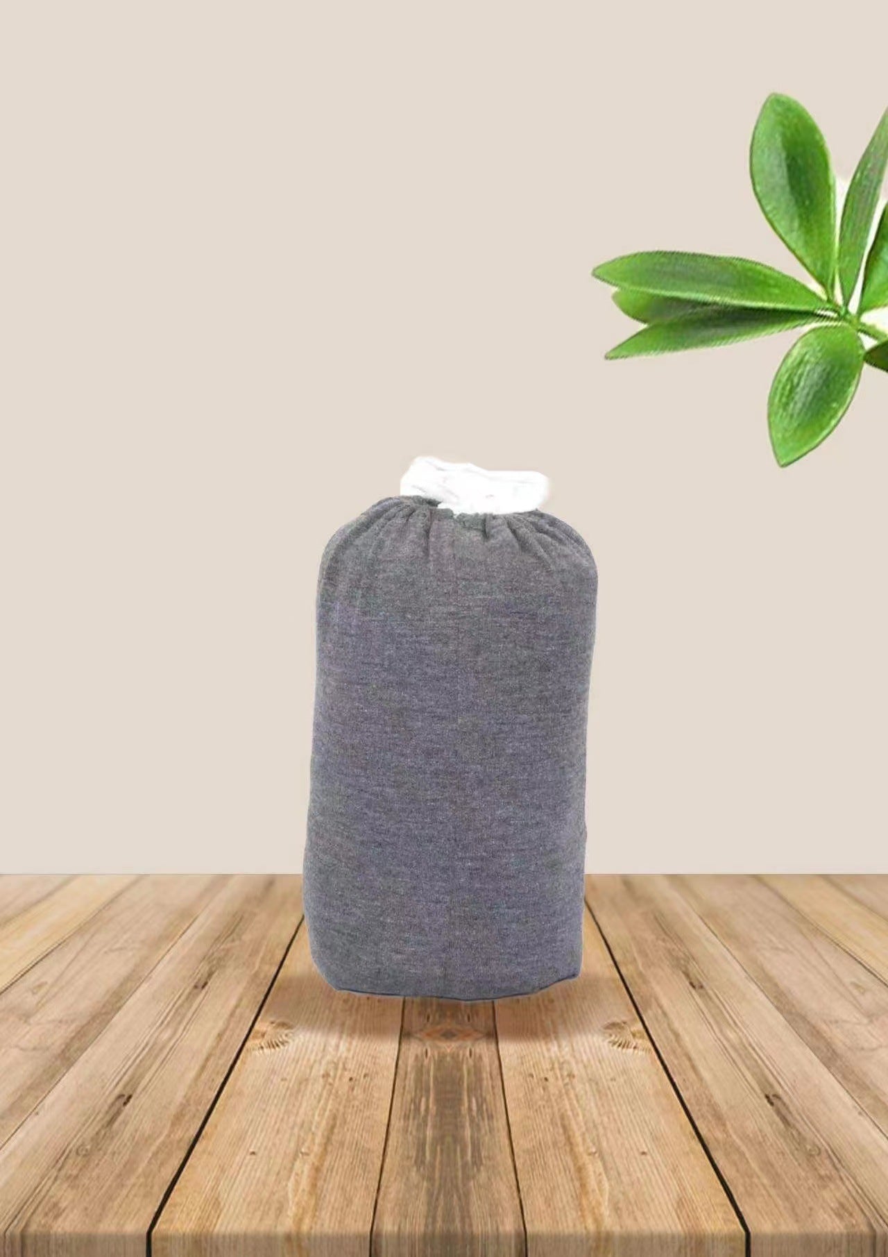 Gray soft cotton baby wrap carrier, rolled up with white trim, on a wooden surface.