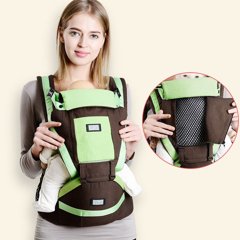 Woman wearing a brown and green ergonomic baby carrier with a comfortable waist base and breathable mesh.