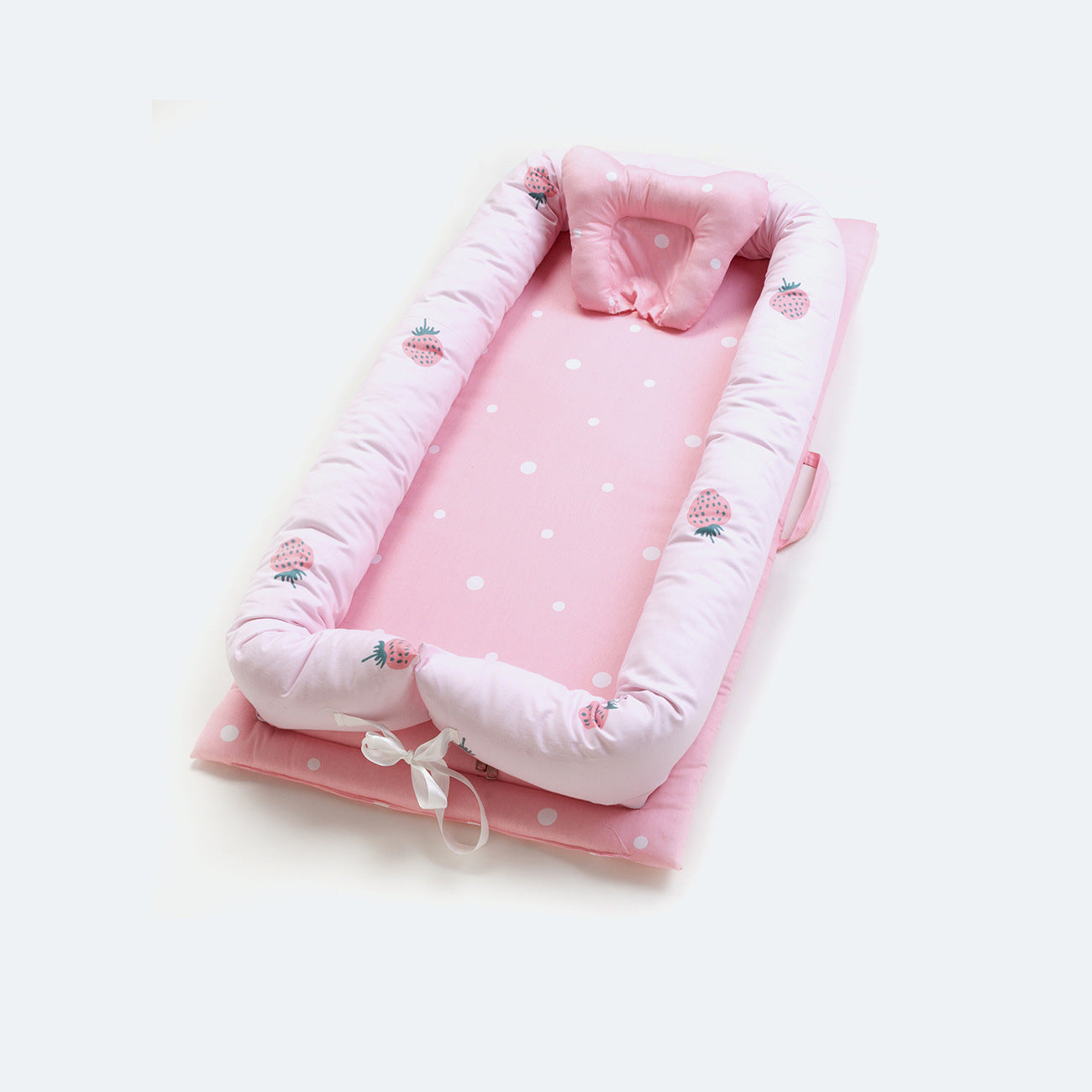 Pink cotton portable baby nest with white polka dots, strawberry print, and head support pillow.