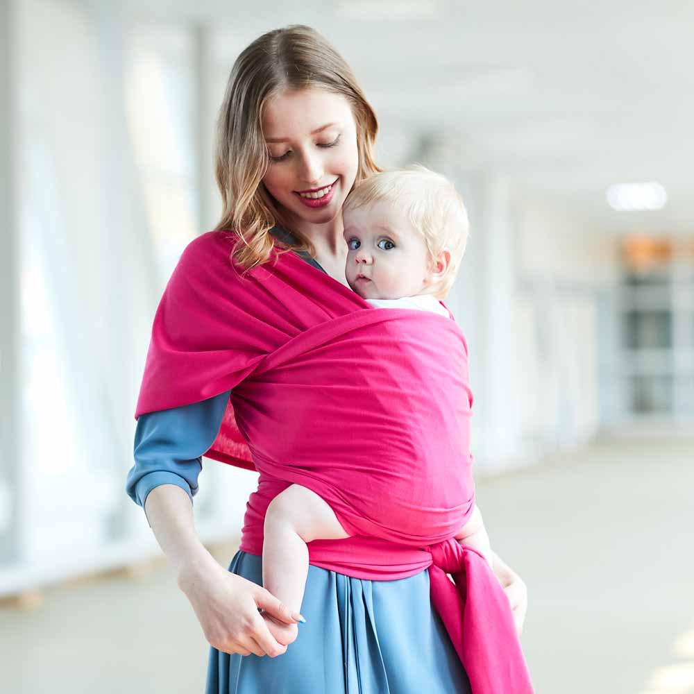 Woman wearing a soft, breathable fuchsia pink baby wrap carrier with a blonde baby.
