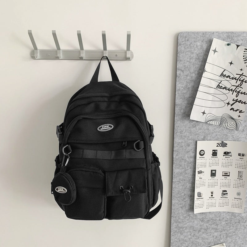 Black nylon student backpack with laptop compartment, multiple pockets, and a small attached pouch.