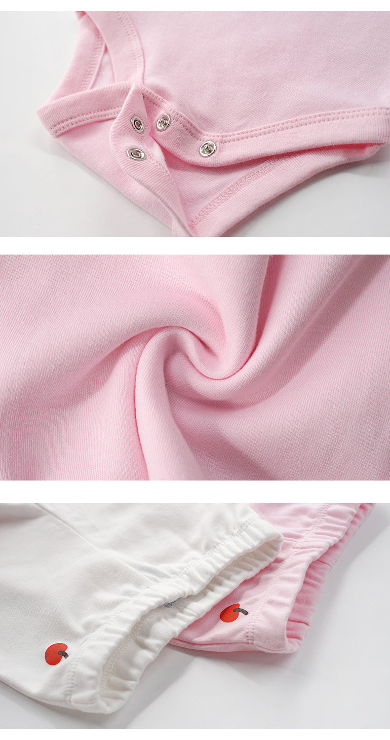 Close-up of soft pink 100% cotton baby clothes, showing snap closures and delicate apple embroidery.