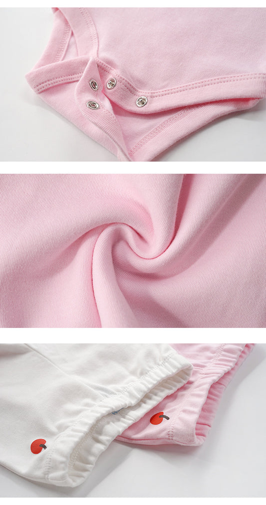 Close-up of soft pink 100% cotton baby clothes, showing snap closures and delicate apple embroidery.