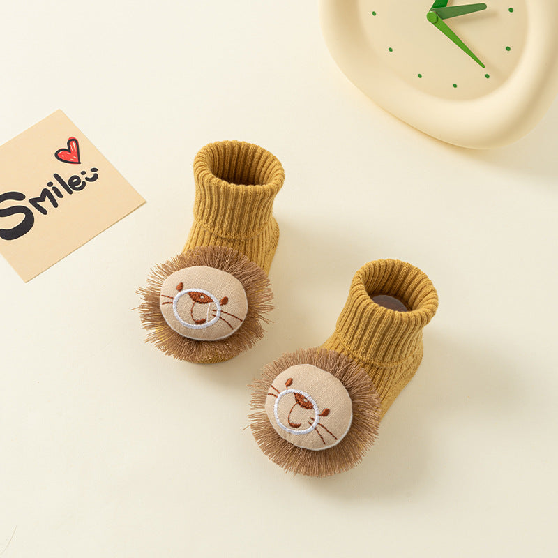 Pair of mustard yellow cotton baby socks with cute 3D lion faces and anti-slip soles.