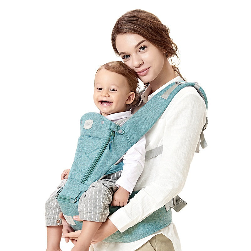 Mother holding a smiling baby in a turquoise ergonomic hip seat carrier with breathable fabric.