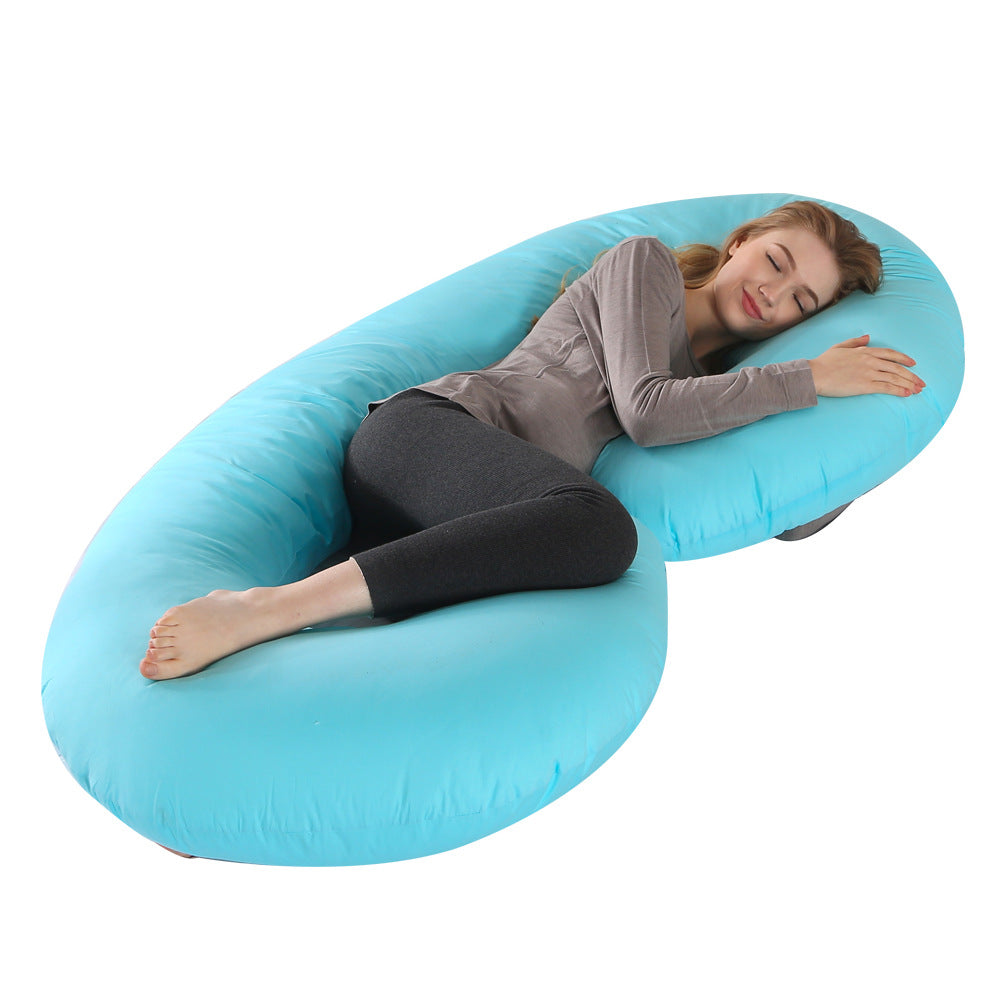 Pregnant woman sleeping comfortably on a large, light blue C-shaped velvet pregnancy pillow.