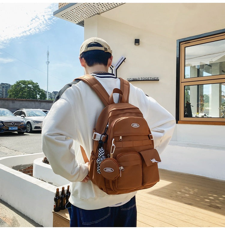 Stylish brown nylon student backpack with multiple pockets, laptop compartment, and checkered keychain.
