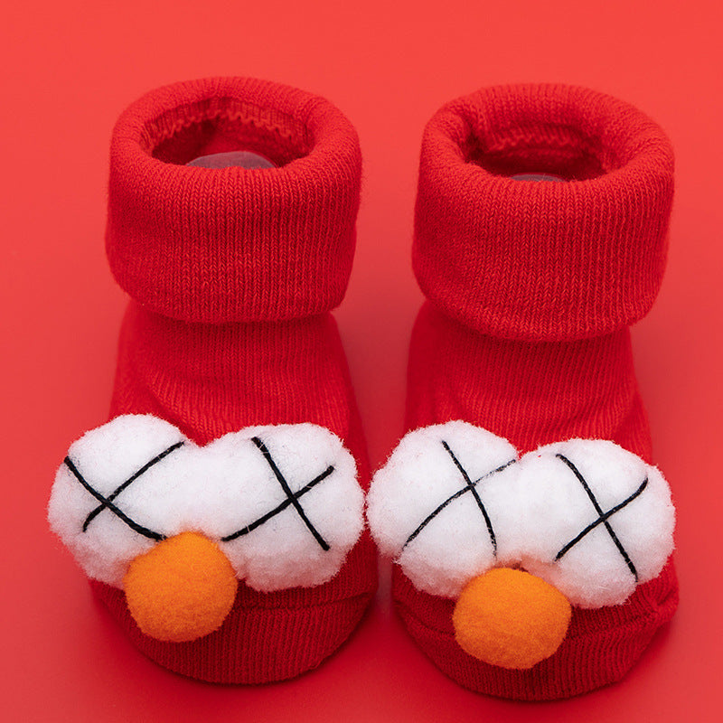 Red cotton baby socks with white plush "X" eyes and orange pom-pom noses, featuring anti-slip soles.