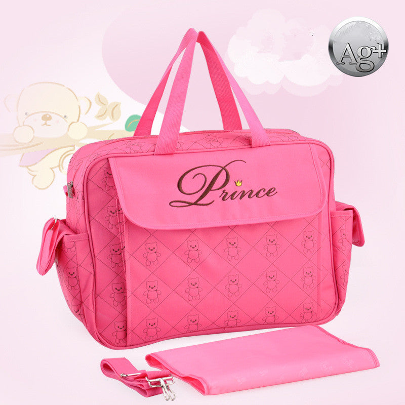 Pink polyester diaper bag with "Prince" embroidery, teddy bear pattern, side pockets, and changing pad.