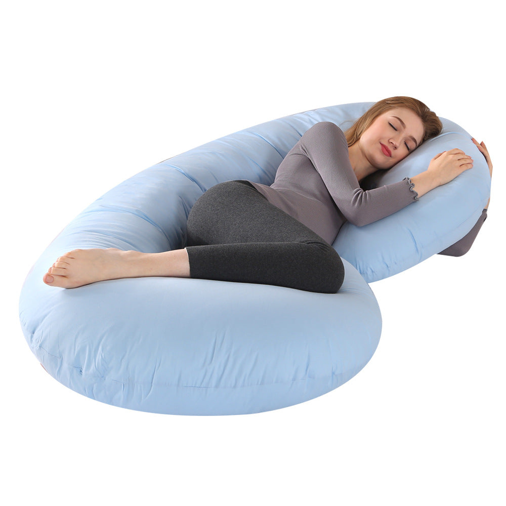 Pregnant woman sleeping soundly on a large, light blue C-shaped velvet pregnancy pillow.