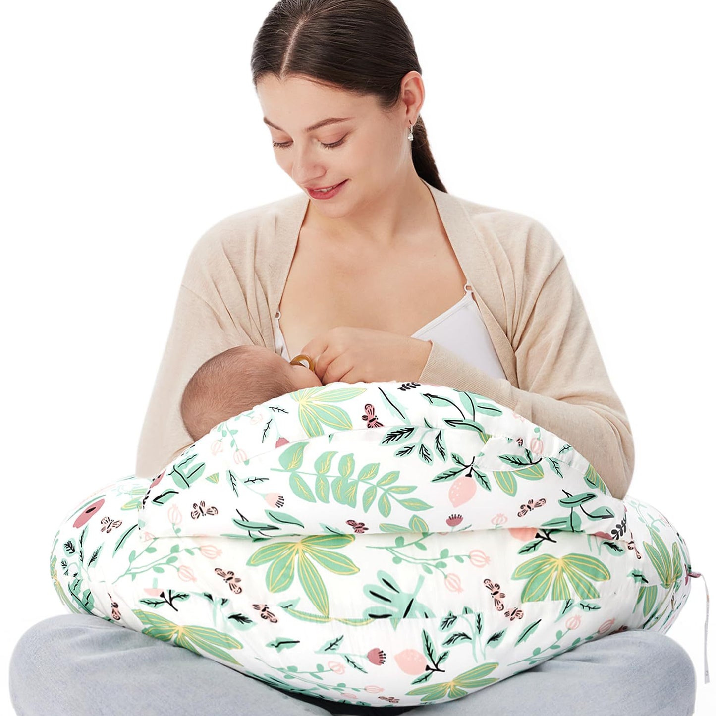 Mother breastfeeding baby using a white nursing pillow with green and pink floral print.