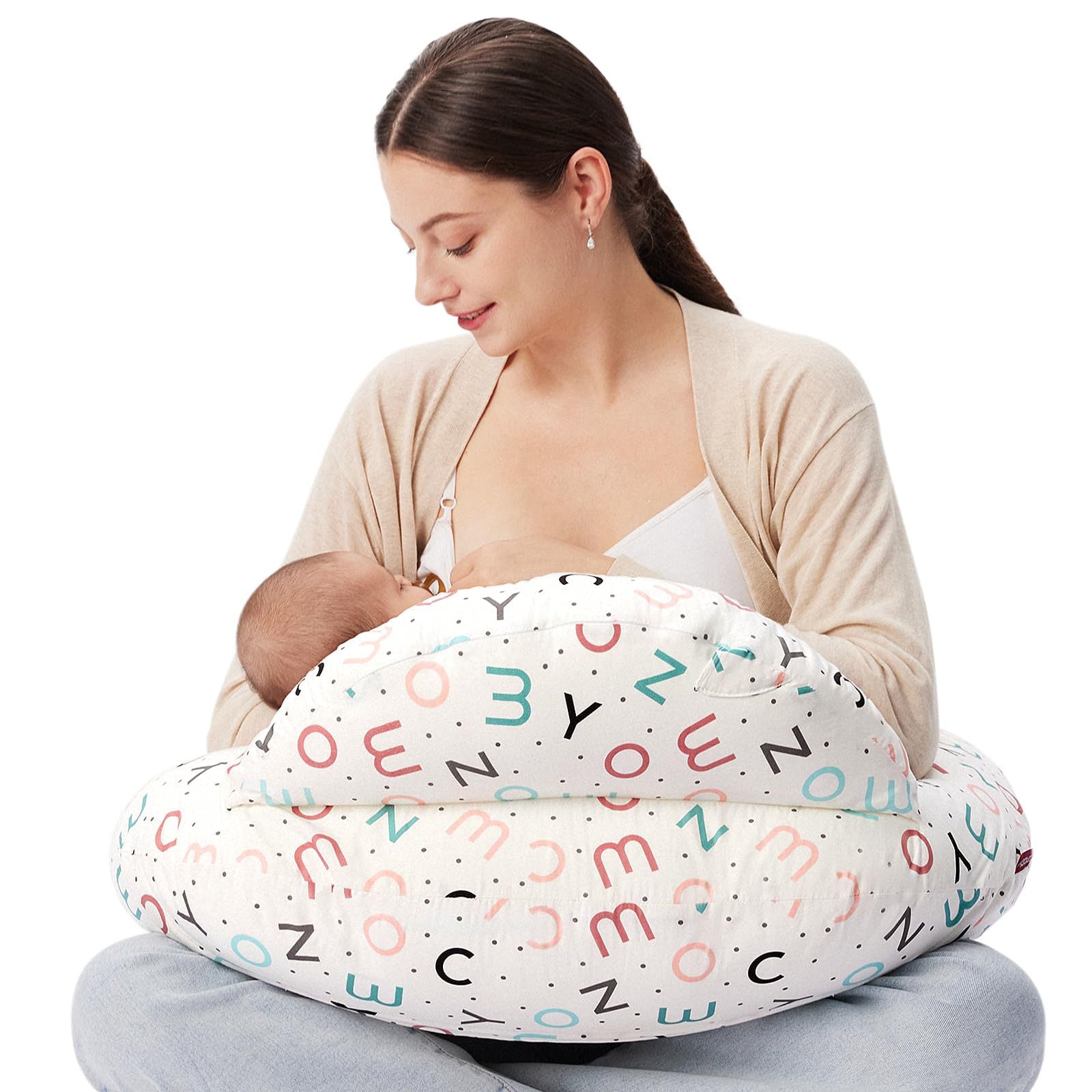 Woman breastfeeding baby with a white multi-use nursing pillow featuring colorful alphabet and dot patterns.