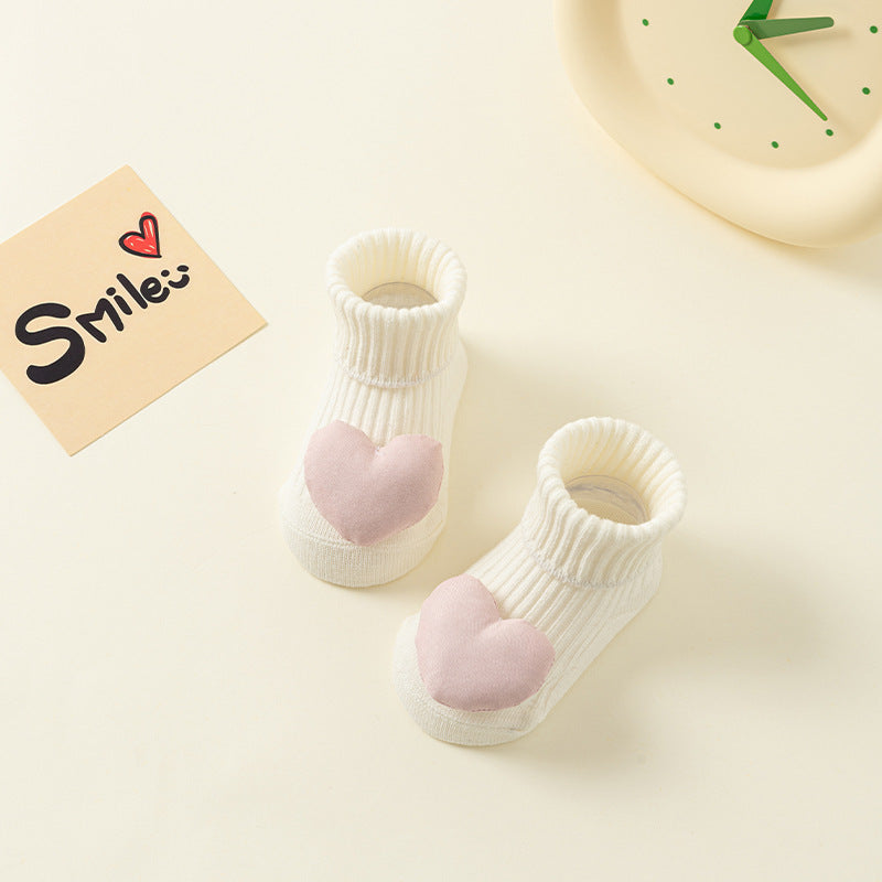 White ribbed cotton baby socks with pink heart design and anti-slip soles.