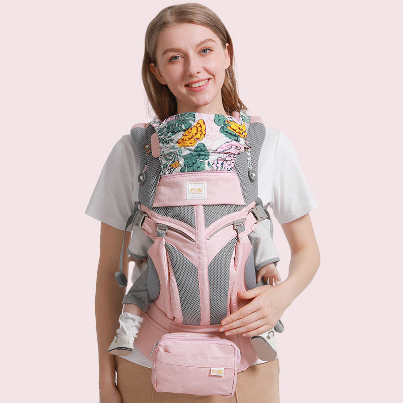 Ergonomic pink cotton baby carrier with floral print, mesh panels, and a detachable pouch.