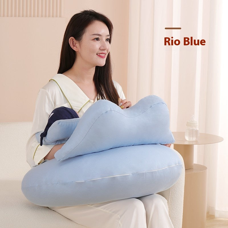 Smiling woman holding a light blue, cloud-shaped nursing pillow and a baby bottle.