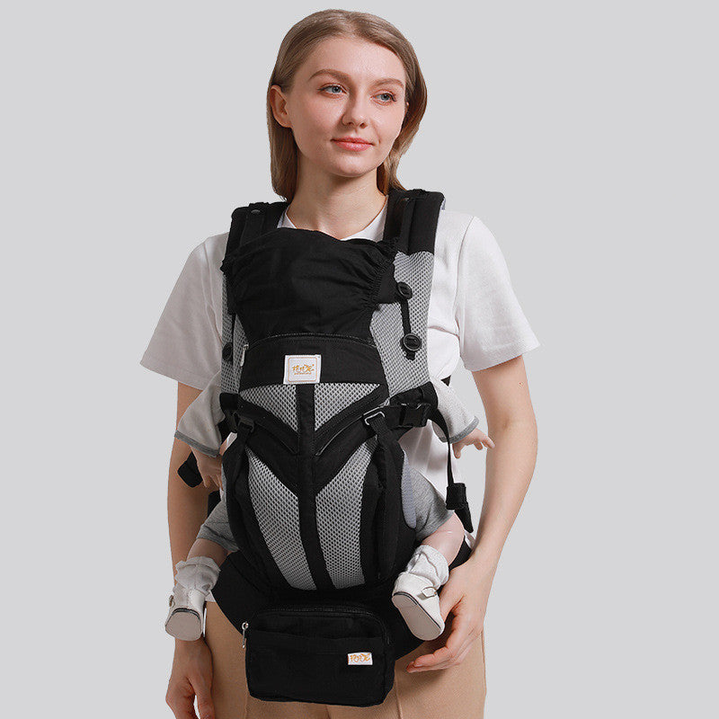 Ergonomic black and gray cotton baby carrier with mesh accents, worn front-facing by a woman.