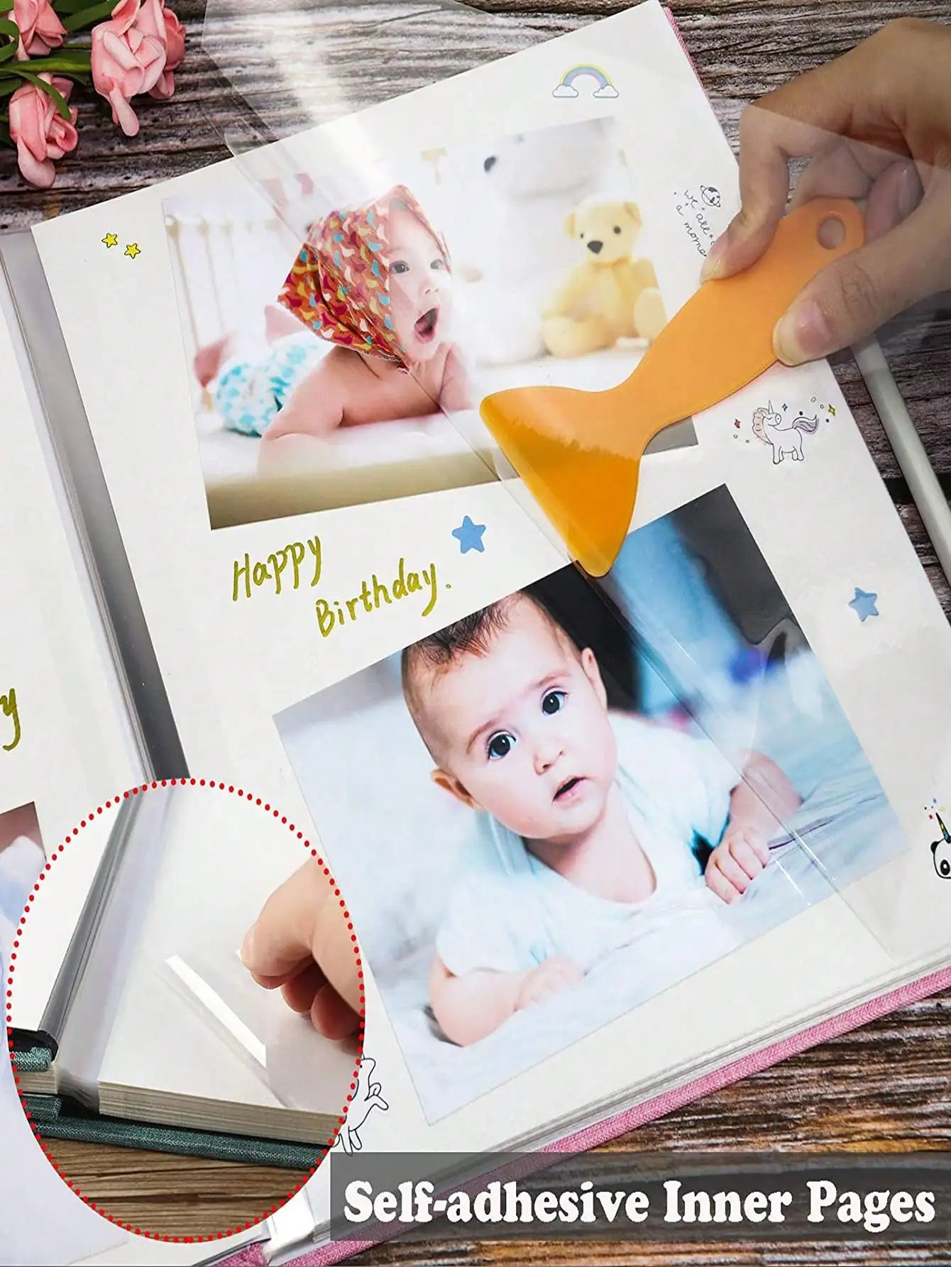 Pink linen baby photo album with self-adhesive pages, showing baby photos and a smoothing tool.