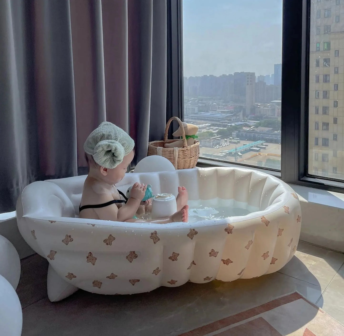 White inflatable baby bathtub with brown bear print, built-in pump, and a baby bathing.