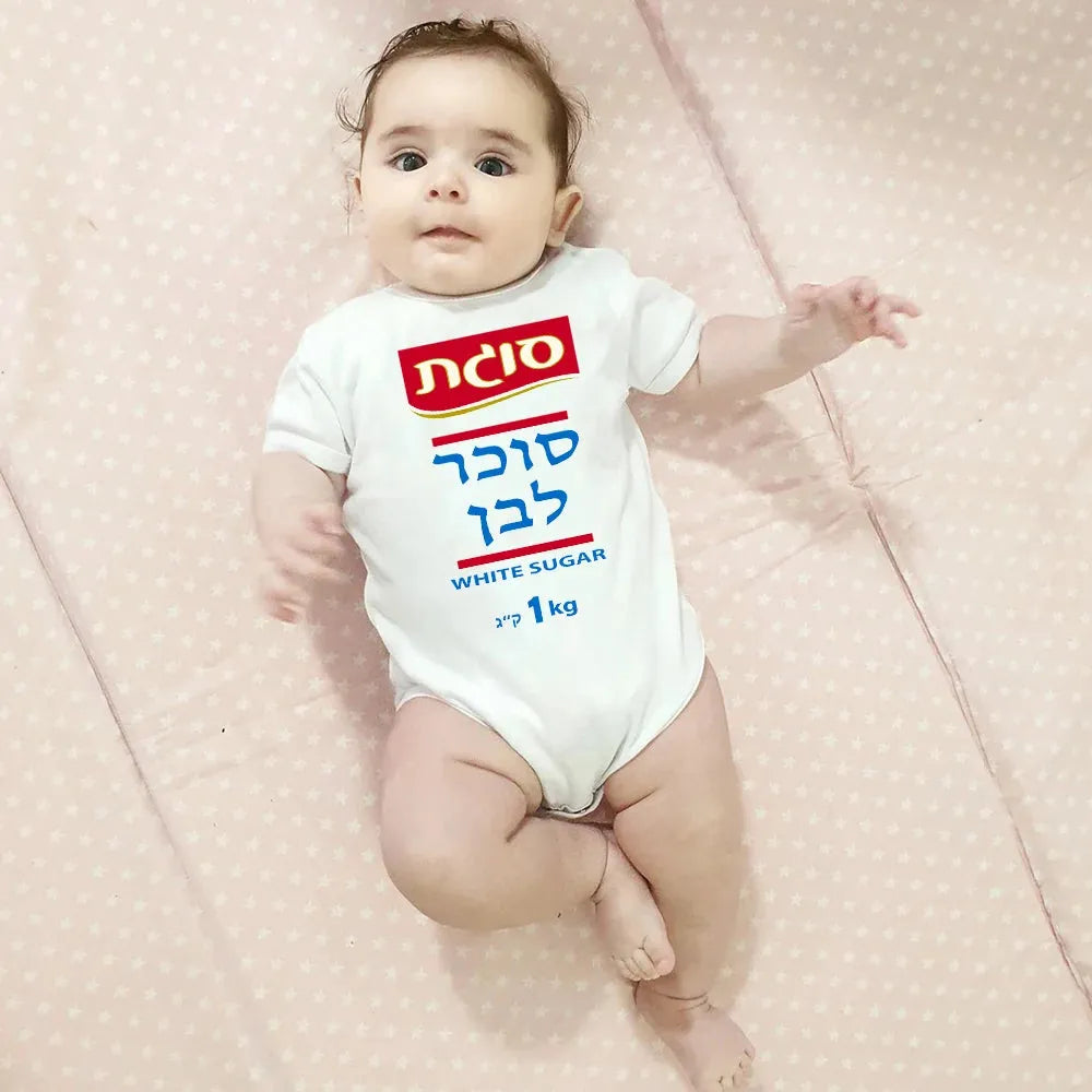 Cute baby in a white short-sleeve bodysuit with a "White Sugar 1kg" graphic, lying on a pink polka-dot blanket.
