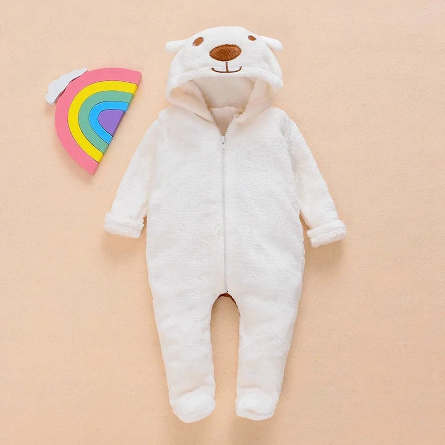 White plush baby bear hooded romper with zipper closure, next to a rainbow toy.