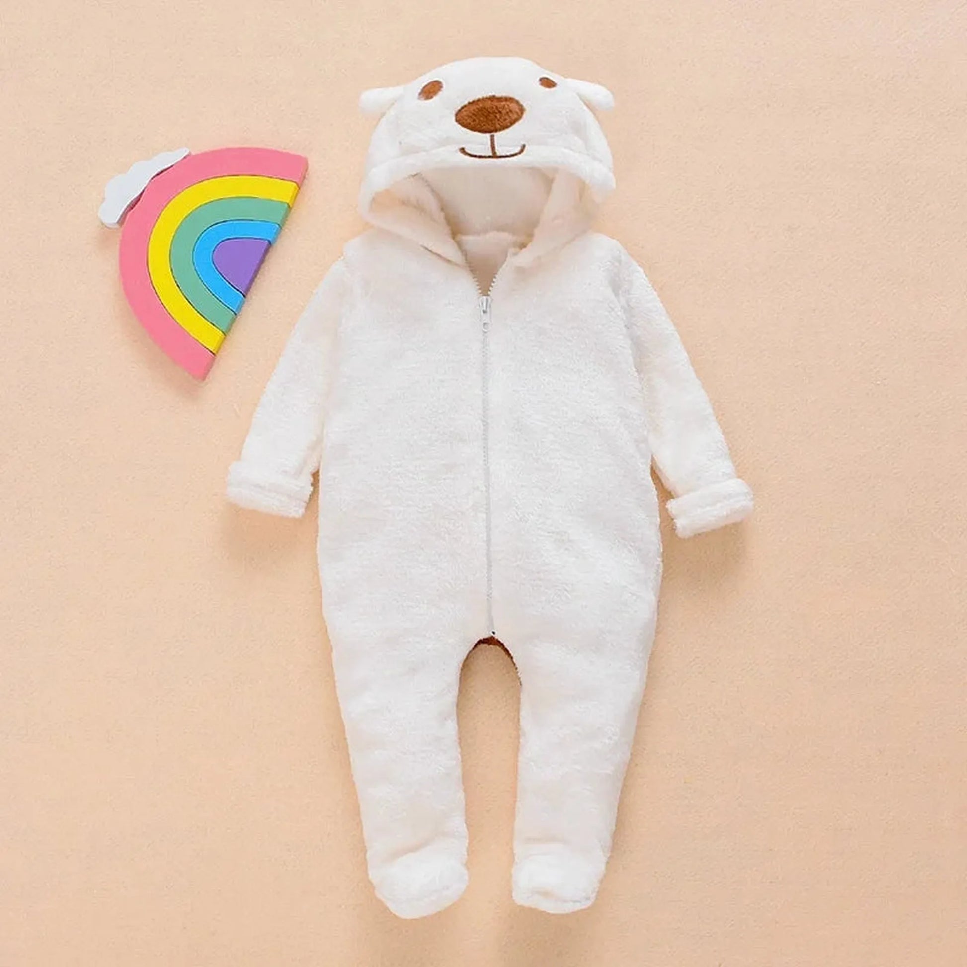 White plush baby bear hooded romper with zipper closure, next to a rainbow toy.