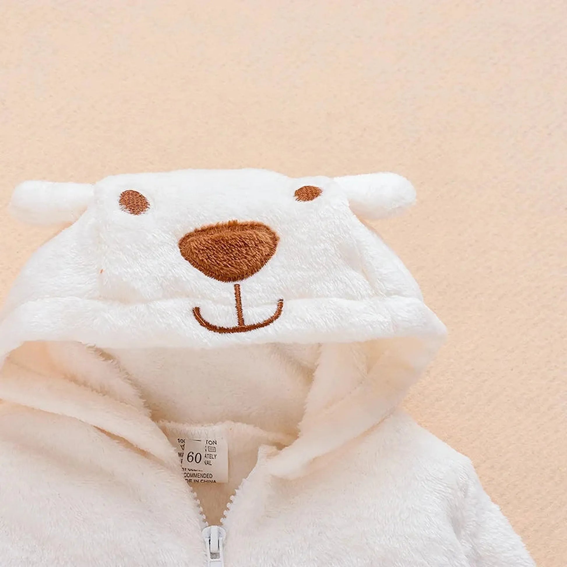 White plush baby bear hooded romper with brown embroidered face and ears.
