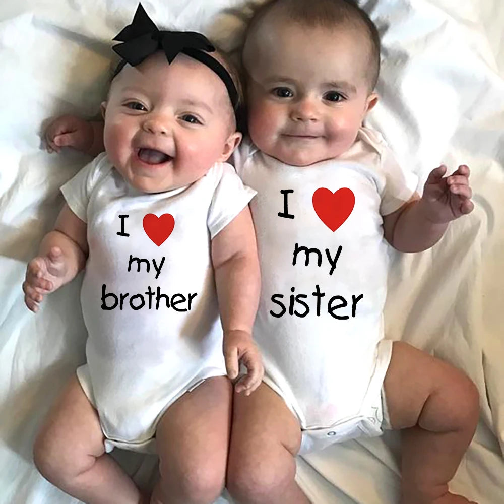 Two happy babies in white short-sleeve bodysuits with "I love my brother" and "I love my sister" prints.