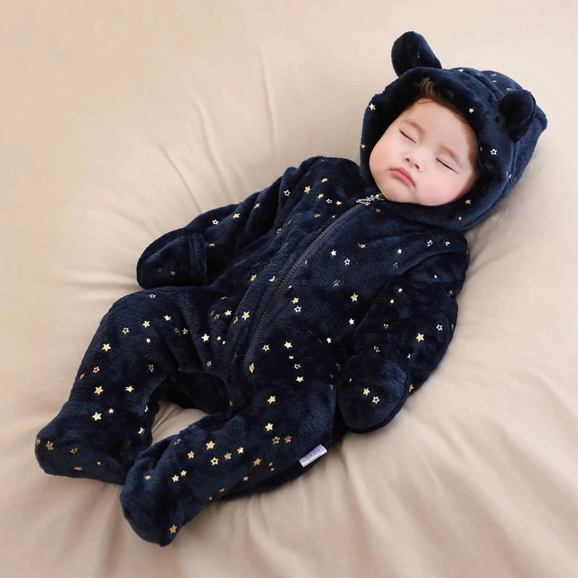 Sleeping baby in a navy flannel romper with gold stars, bear ears, and a full zipper.