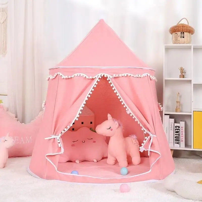 Pink cotton foldable castle play tent for kids with pom-pom trim, unicorn toy, and pillows inside.