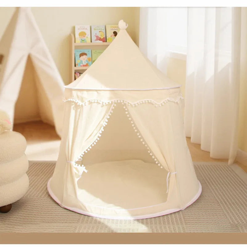 Foldable cream cotton castle play tent for kids with pom-pom trim and open entrance.