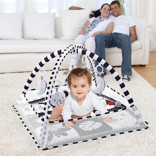 Baby activity gym with black and white striped arch, soft mat, and hanging toys.
