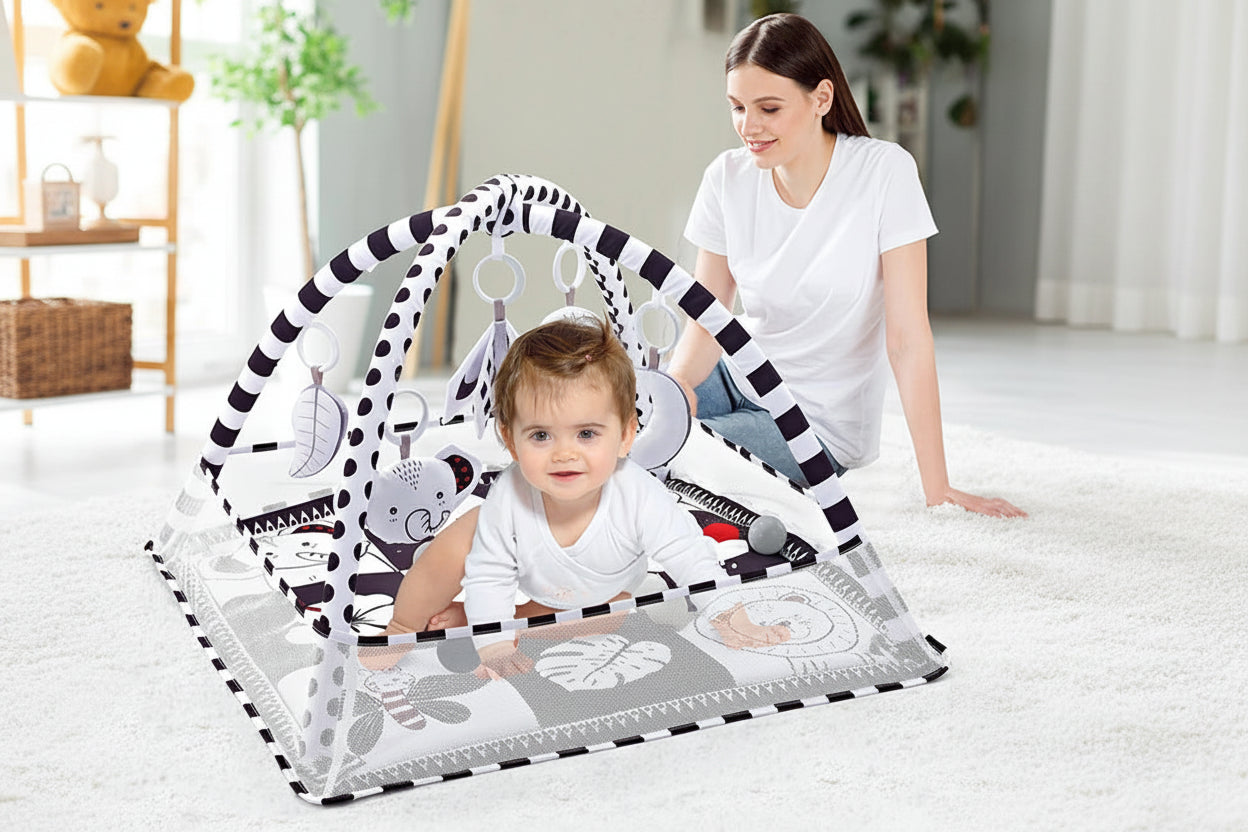 Black and white baby activity gym with arch, hanging toys, and a smiling baby.