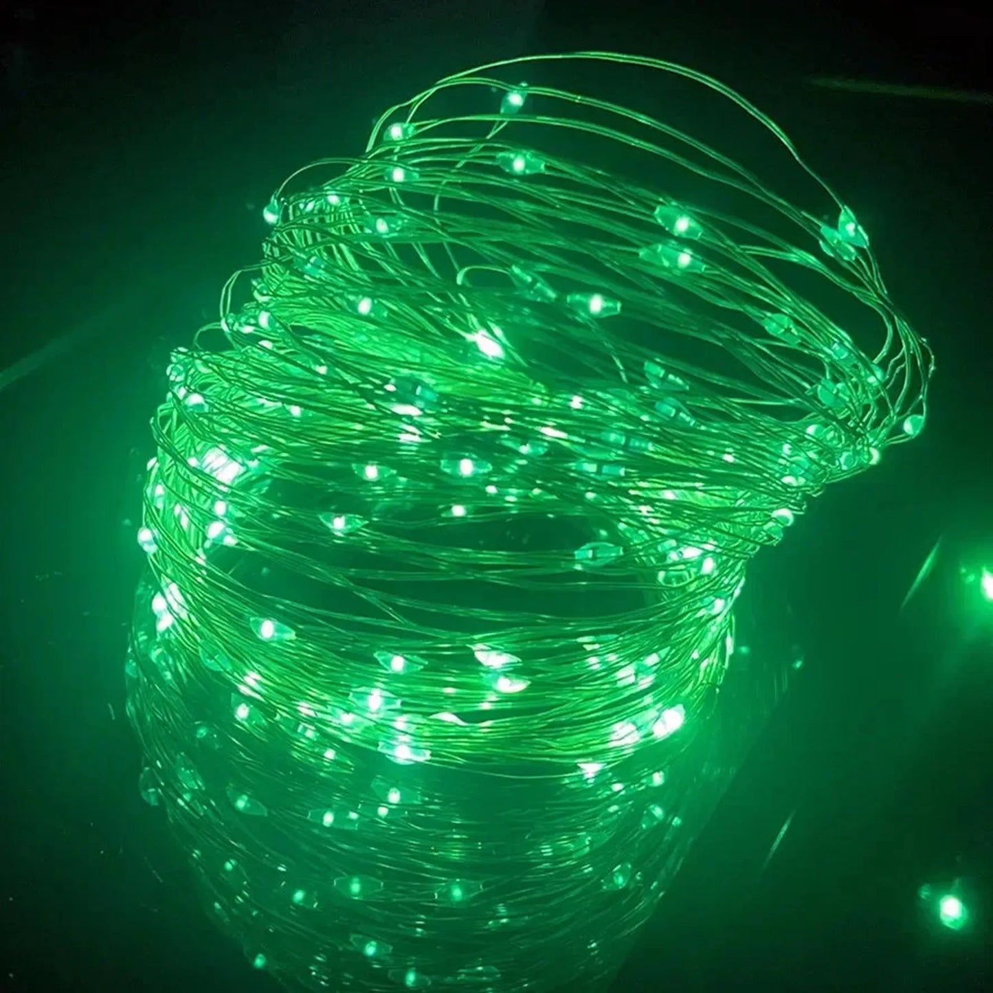 Coiled green LED string lights with small, bright bulbs, ideal for room decor.